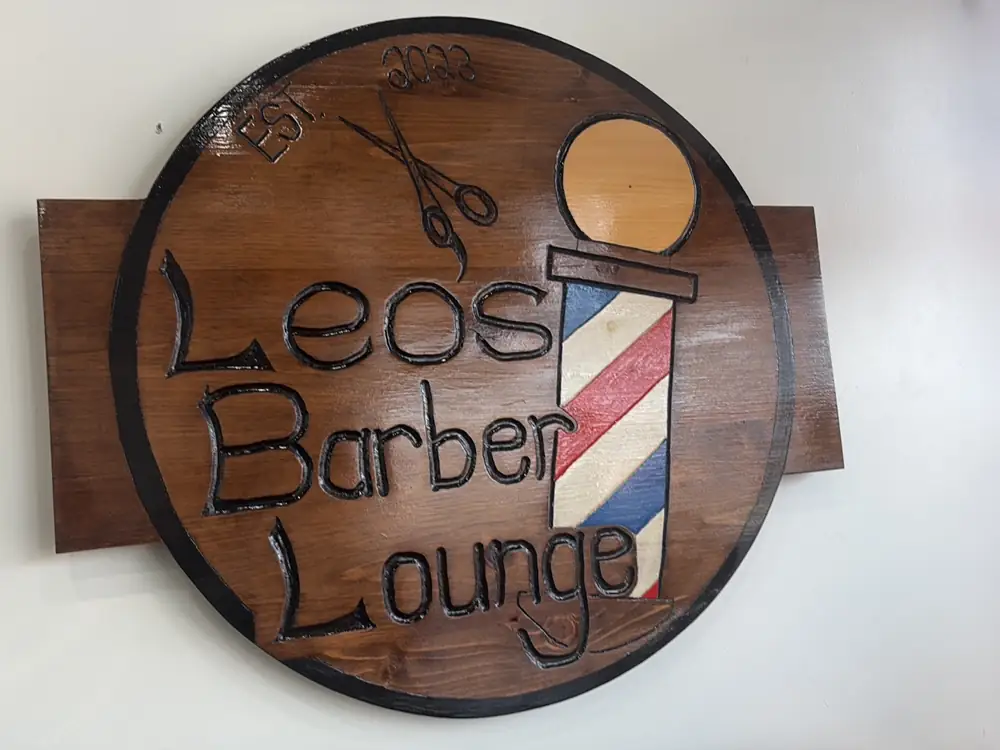 Hand-carved Leo’s Barber Lounge wood sign with a barber pole